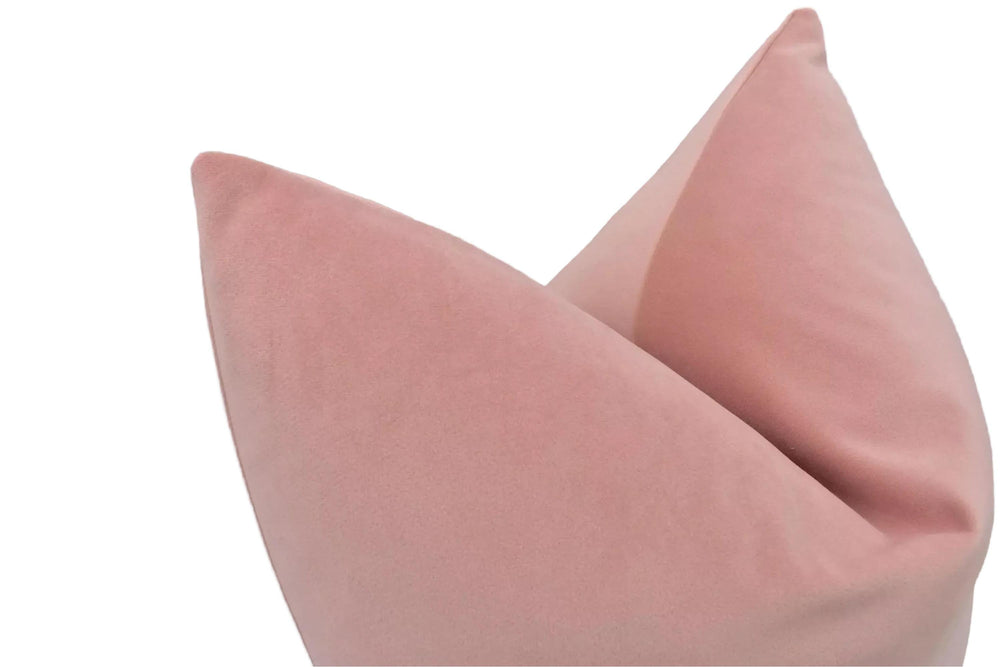 A close-up image of a pink velvet pillow against a white background.