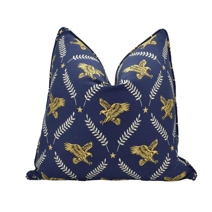 a navy blue pillow with a gold eagle and leaf pattern design.