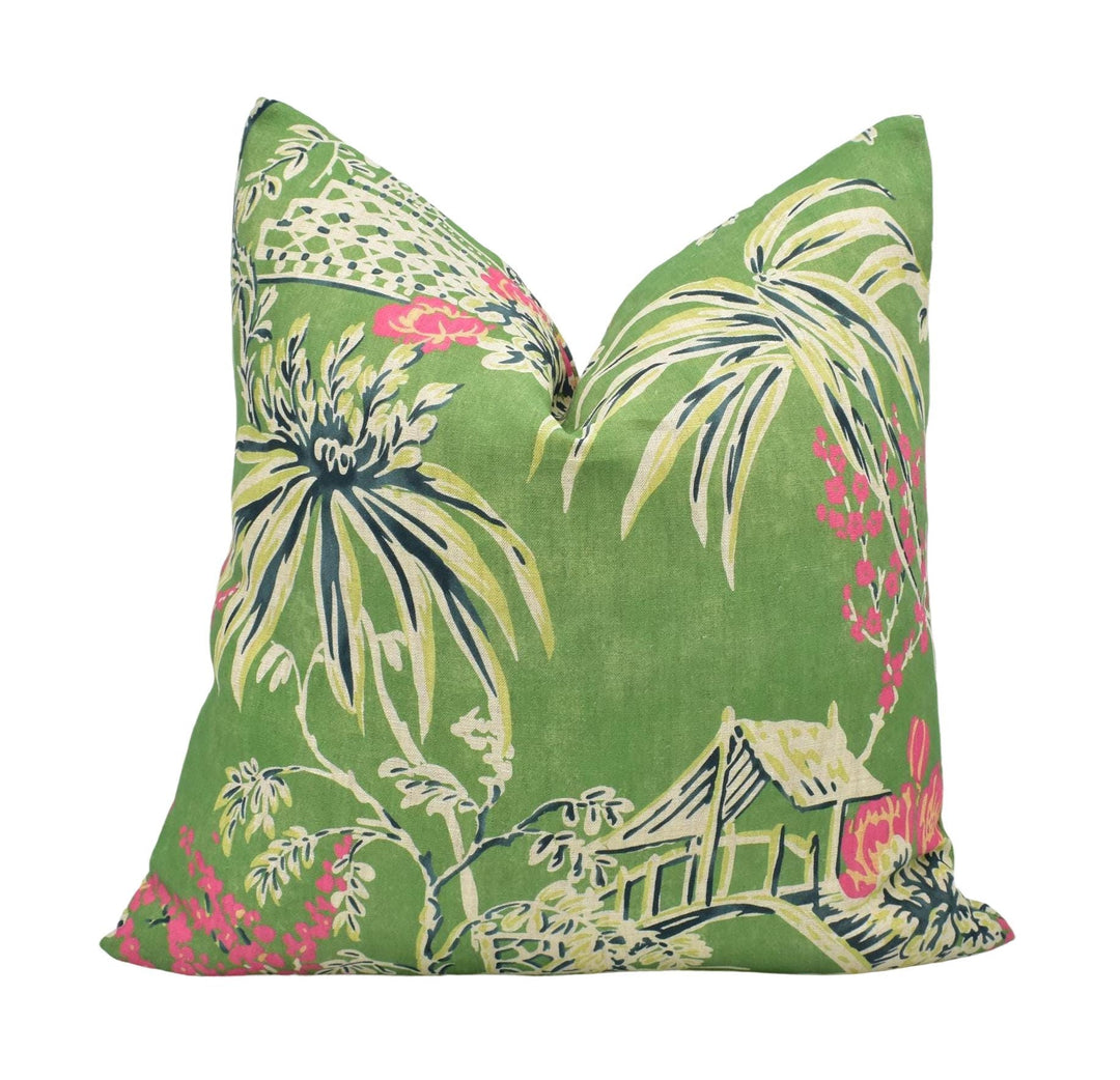 A green throw pillow with a tropical print design featuring palm trees, flowers, and a house.
