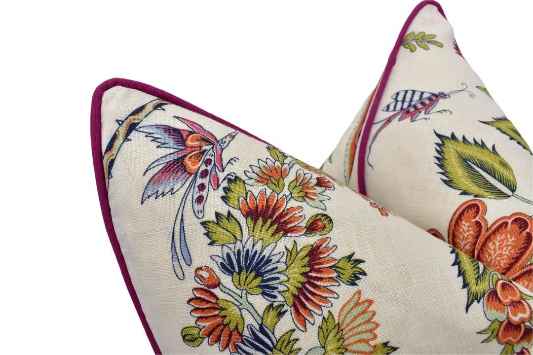 two decorative pillows with a floral pattern. The pillows have a vibrant and colorful design, featuring various flowers and leaves in shades of orange, green, and purple. The pillows are positioned close together, creating a visually appealing arrangement.