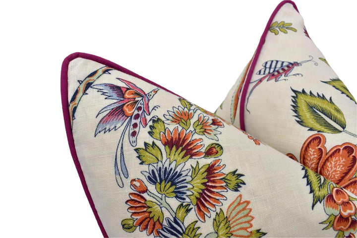 two decorative pillows with a floral pattern. The pillows have a vibrant and colorful design, featuring various flowers and leaves in shades of orange, green, and purple. The pillows are positioned close together, creating a visually appealing arrangement.