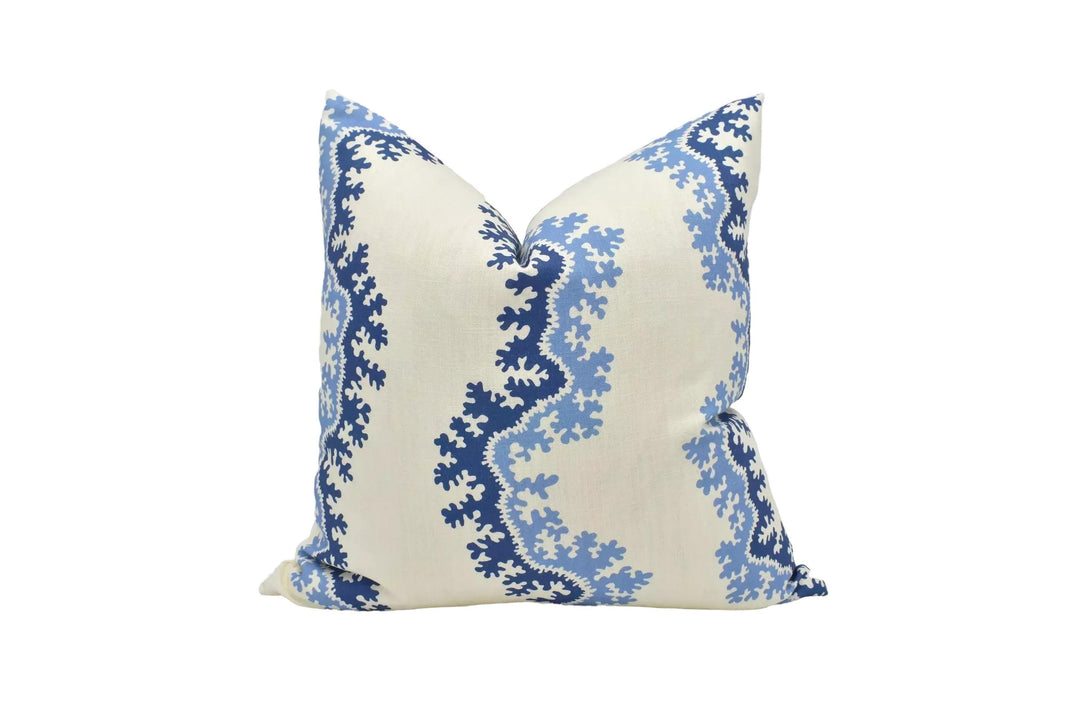 A decorative pillow with a blue and white floral pattern on a cream-colored background.