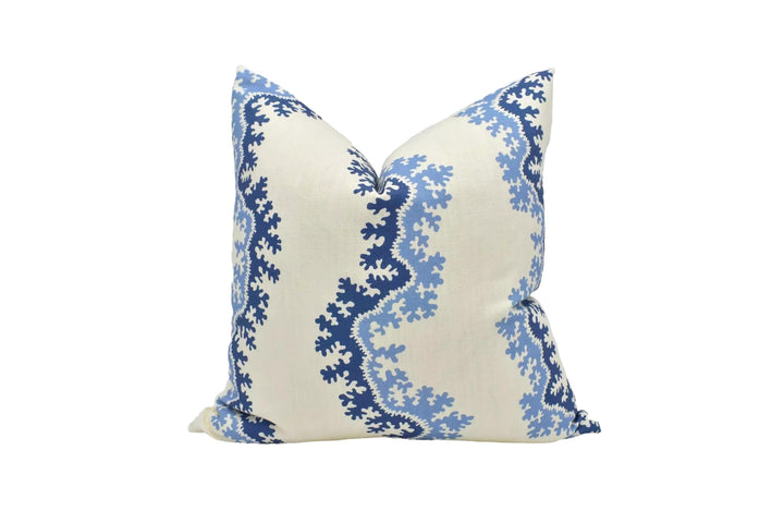 A decorative pillow with a blue and white floral pattern on a cream-colored background.