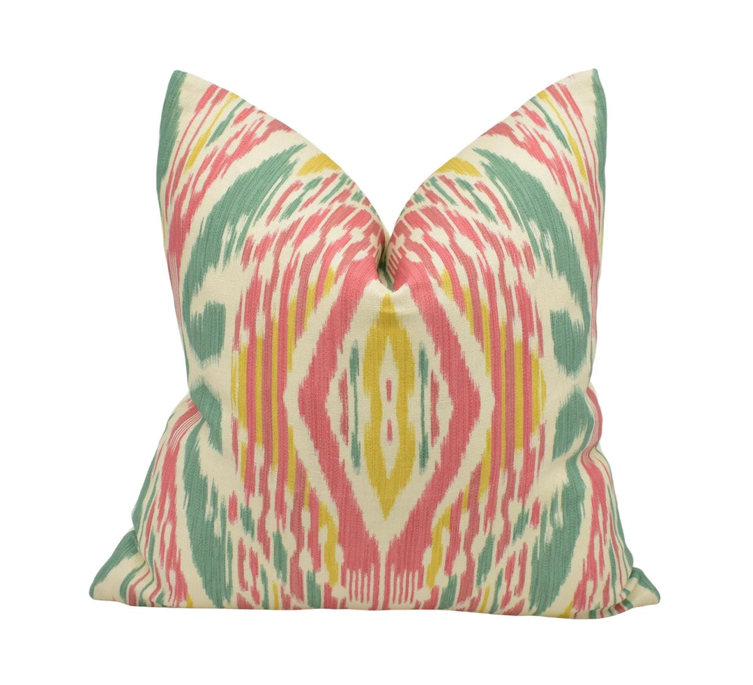 A colorful, patterned pillow with a vibrant design in shades of green, pink, and yellow.