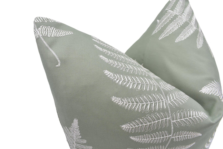 a close-up view of a green pillow with a white leaf pattern.