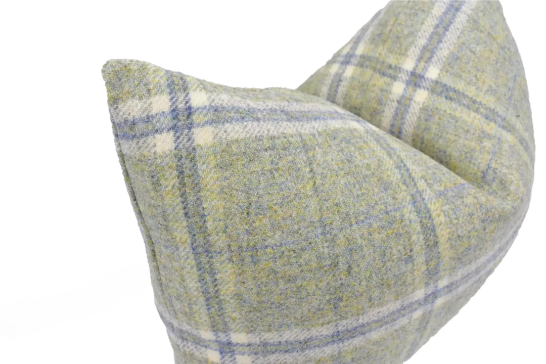 A close-up image of a plaid pillow with a light green and blue color scheme.