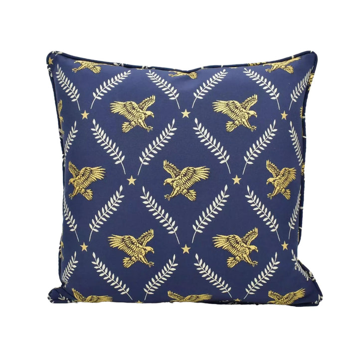 A navy blue throw pillow with a repeating pattern of gold eagle and leaf designs.