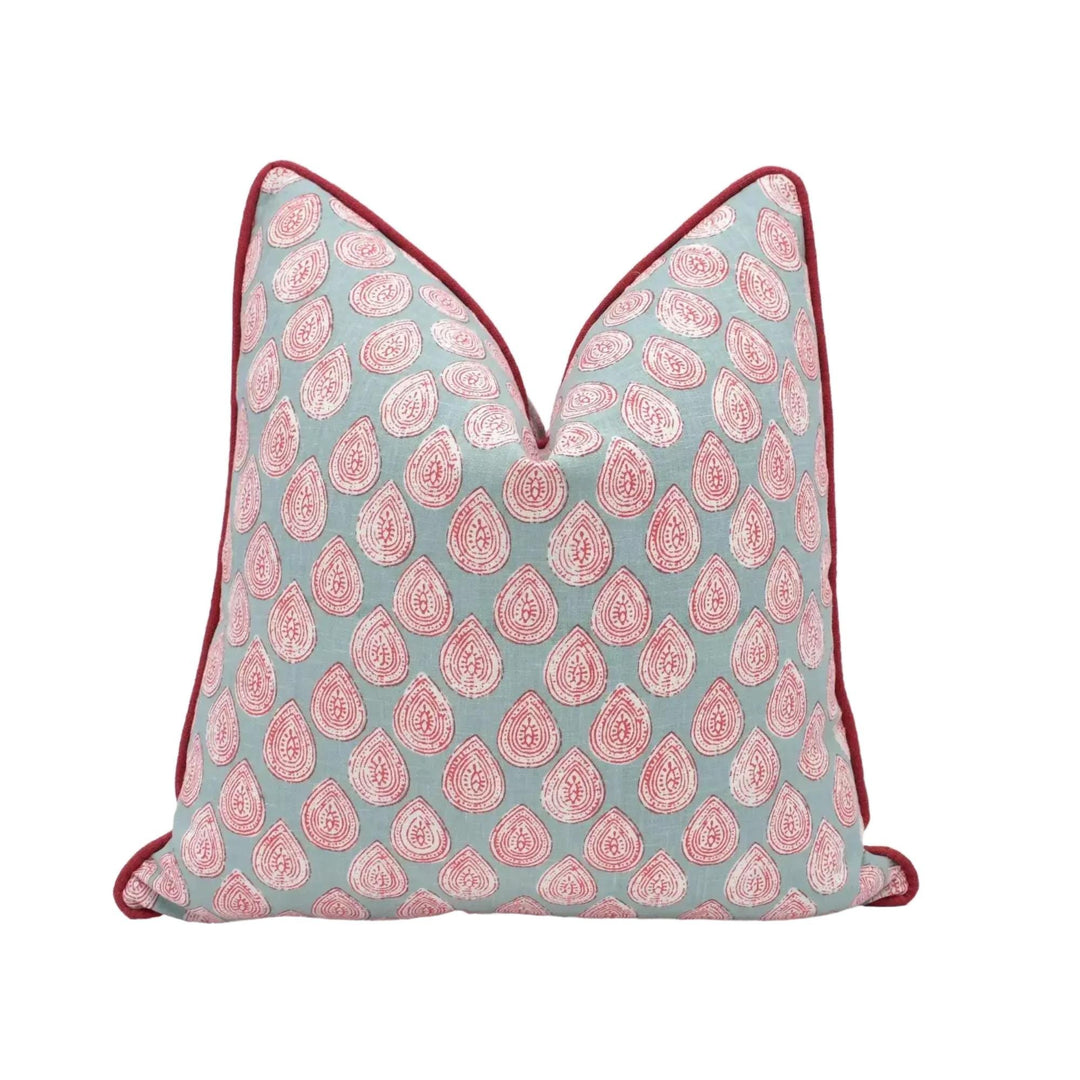 A decorative pillow with a repeating pattern of red and white teardrop shapes on a light blue background.
