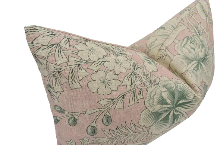 a decorative pillow with a floral pattern in shades of pink and green.