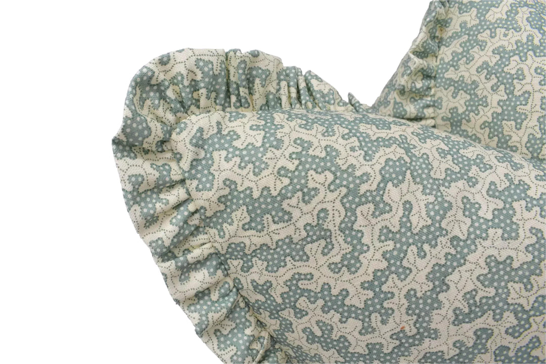 A close-up view of a decorative pillow with a ruffled edge and a patterned fabric.