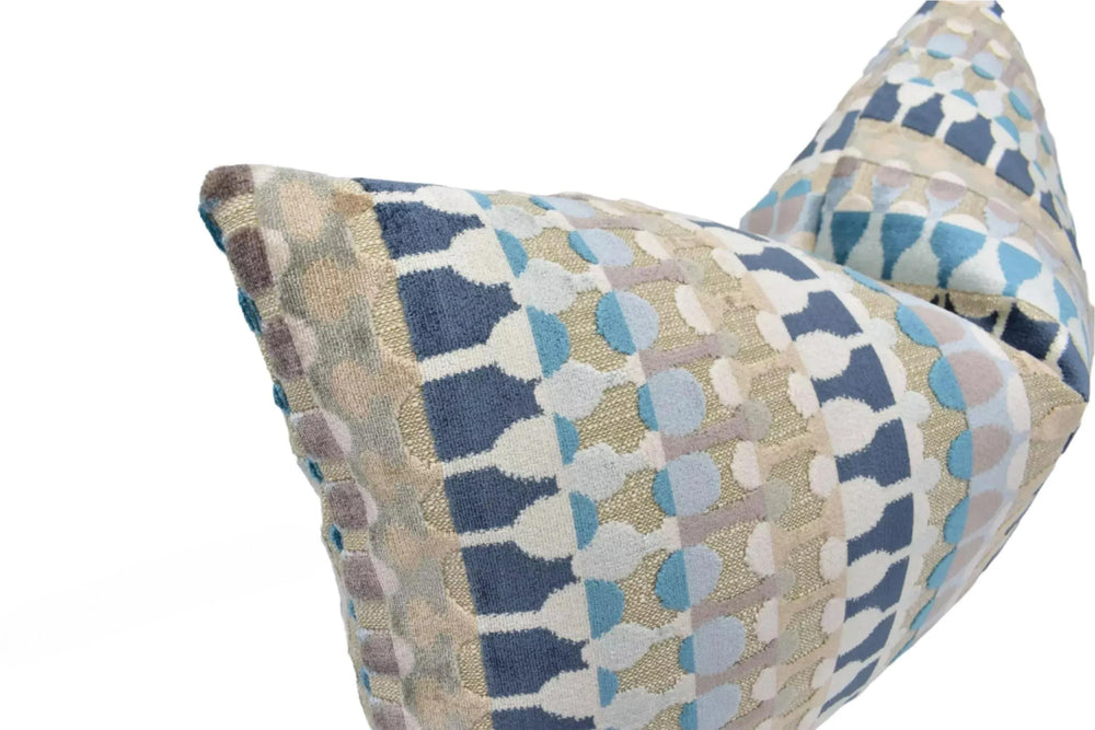 a close-up view of a decorative pillow with a geometric pattern in shades of blue, gray, and beige.