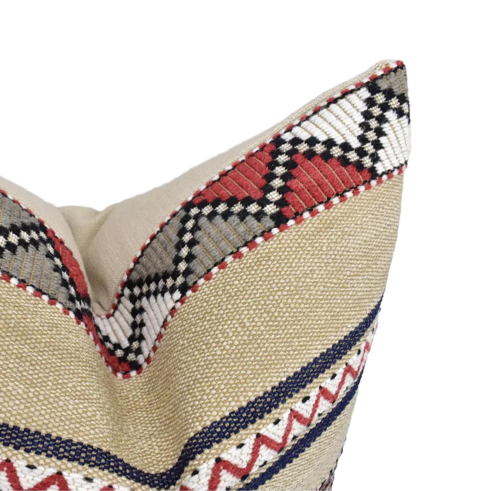 A close-up view of a decorative pillow with a beige fabric and a pattern of red, black, and white stripes.