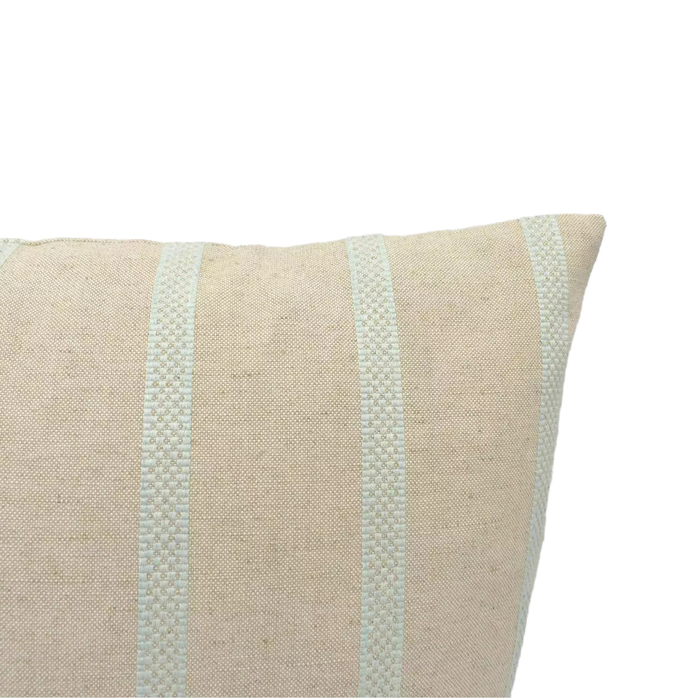 A beige pillow with a striped pattern is shown against a plain white wall.