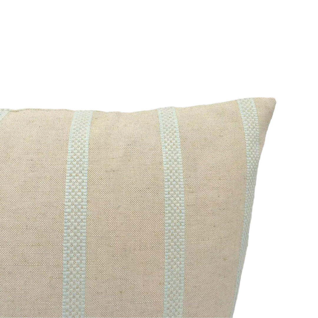 A beige pillow with a striped pattern is shown against a plain white wall.