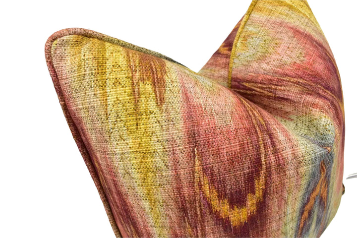 A close-up image of a colorful, textured fabric pillow with a vibrant, abstract pattern in shades of red, yellow, and orange.