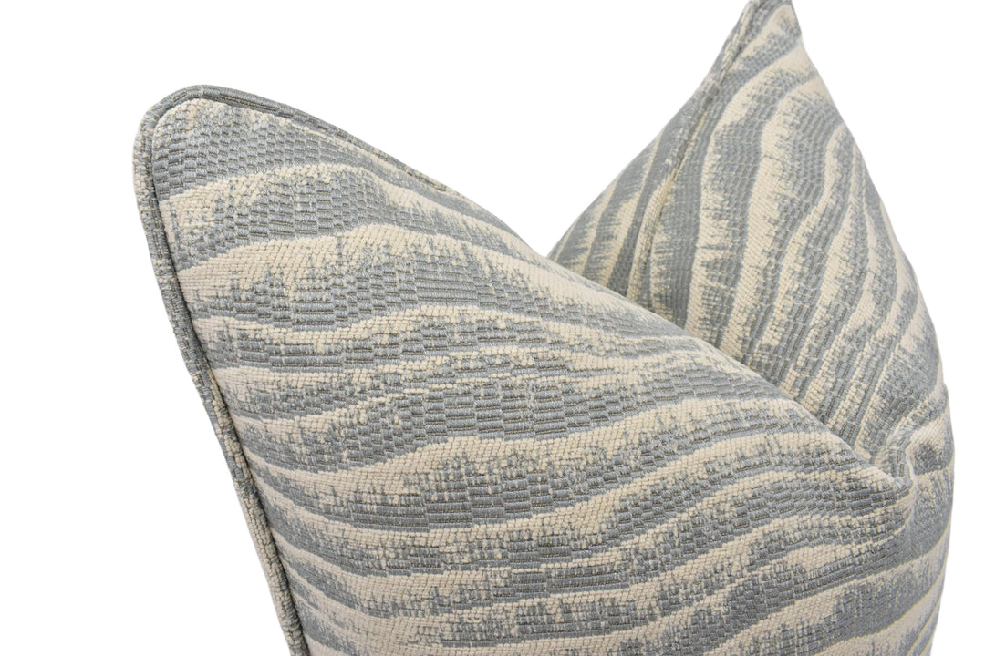 A close-up view of a gray and white striped pillow with a textured, woven pattern.