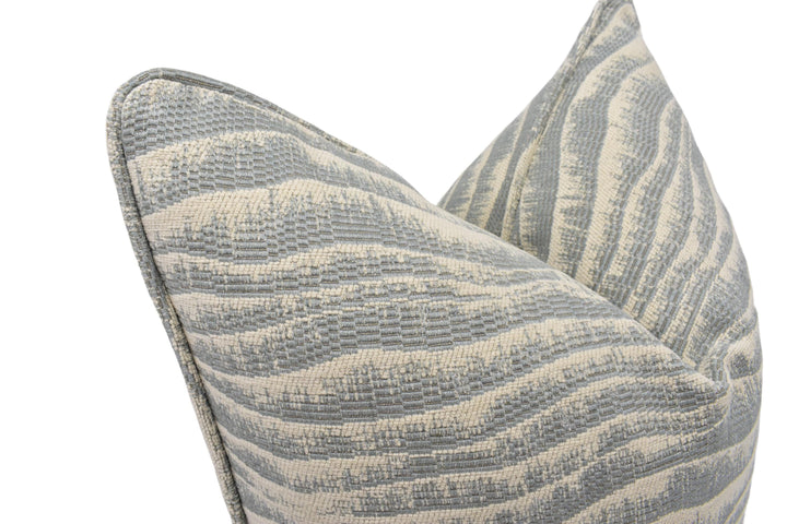 A close-up view of a gray and white striped pillow with a textured, woven pattern.