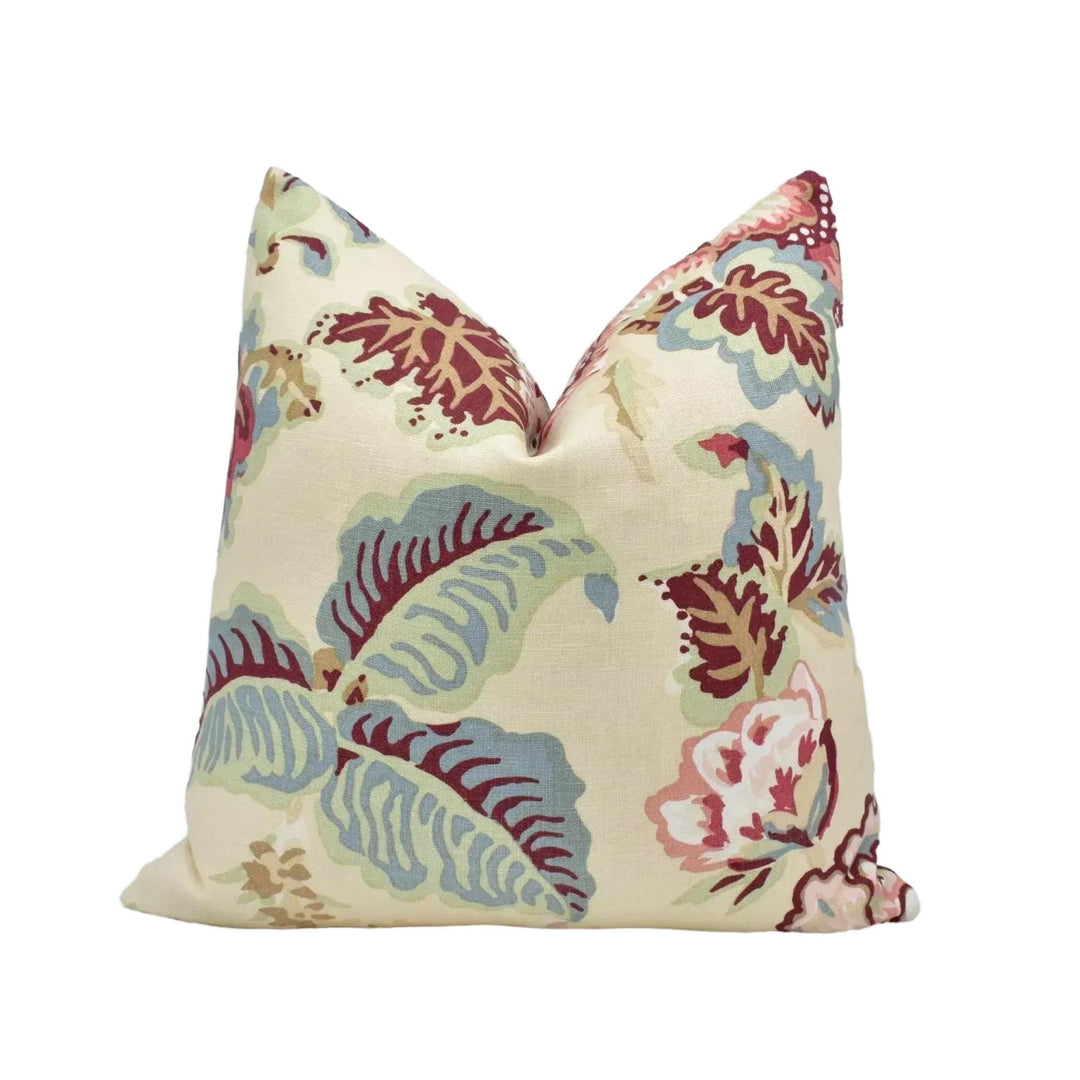 a decorative pillow with a floral pattern in shades of green, red, and white.