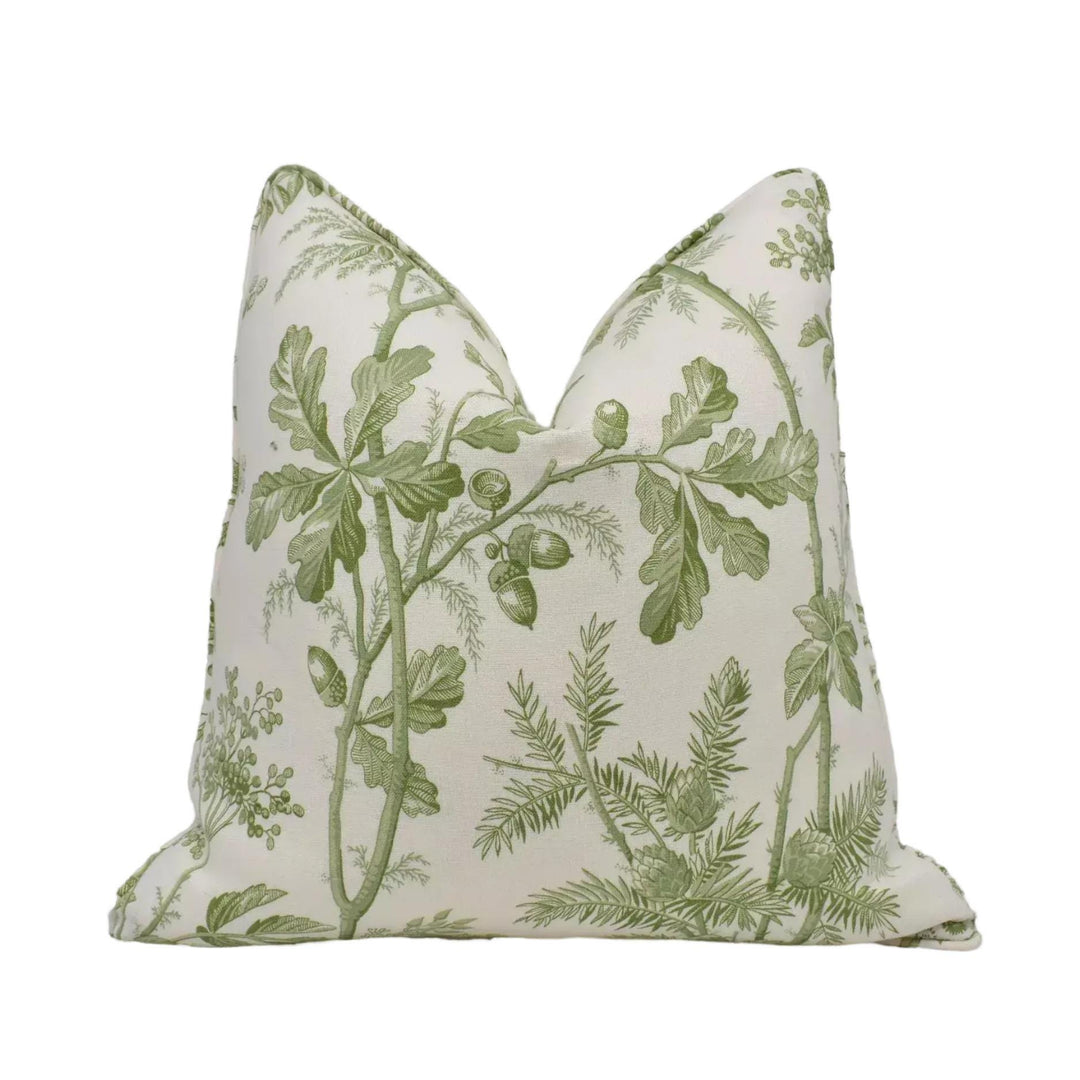 A white pillow with a green leaf and branch pattern.