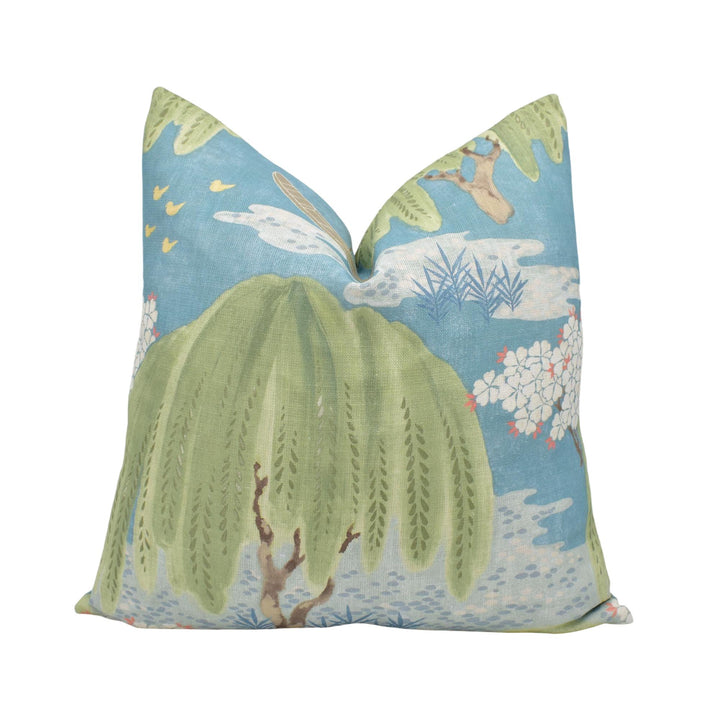 a decorative pillow with a vibrant, nature-inspired design. The pillow has a green and blue color scheme, with a large green leaf and a smaller blue leaf as the main elements. The design also includes a blue bird and a white flower, adding to the overall visual appeal of the pillow.