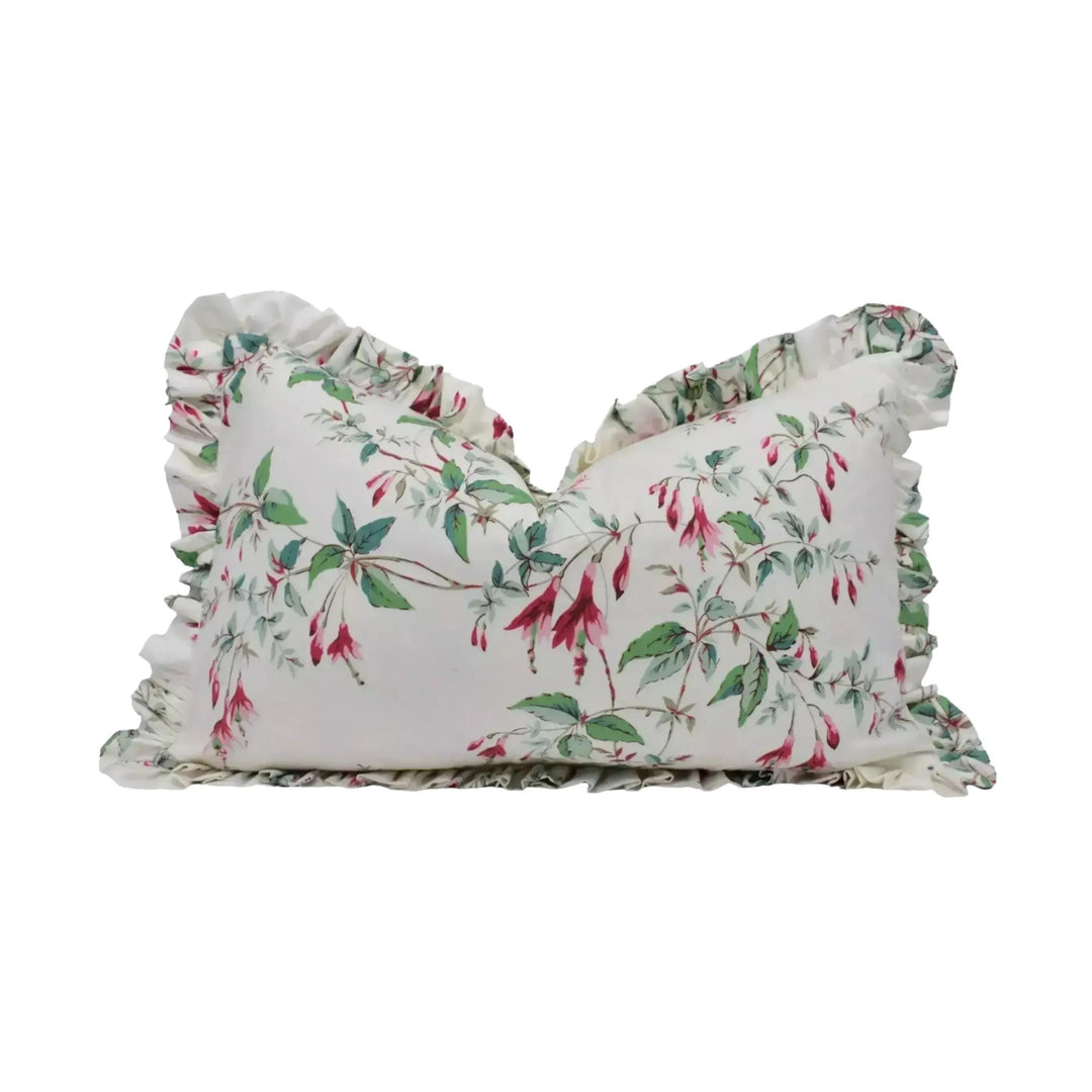 A white pillow with a floral print design, featuring red and green flowers and leaves.