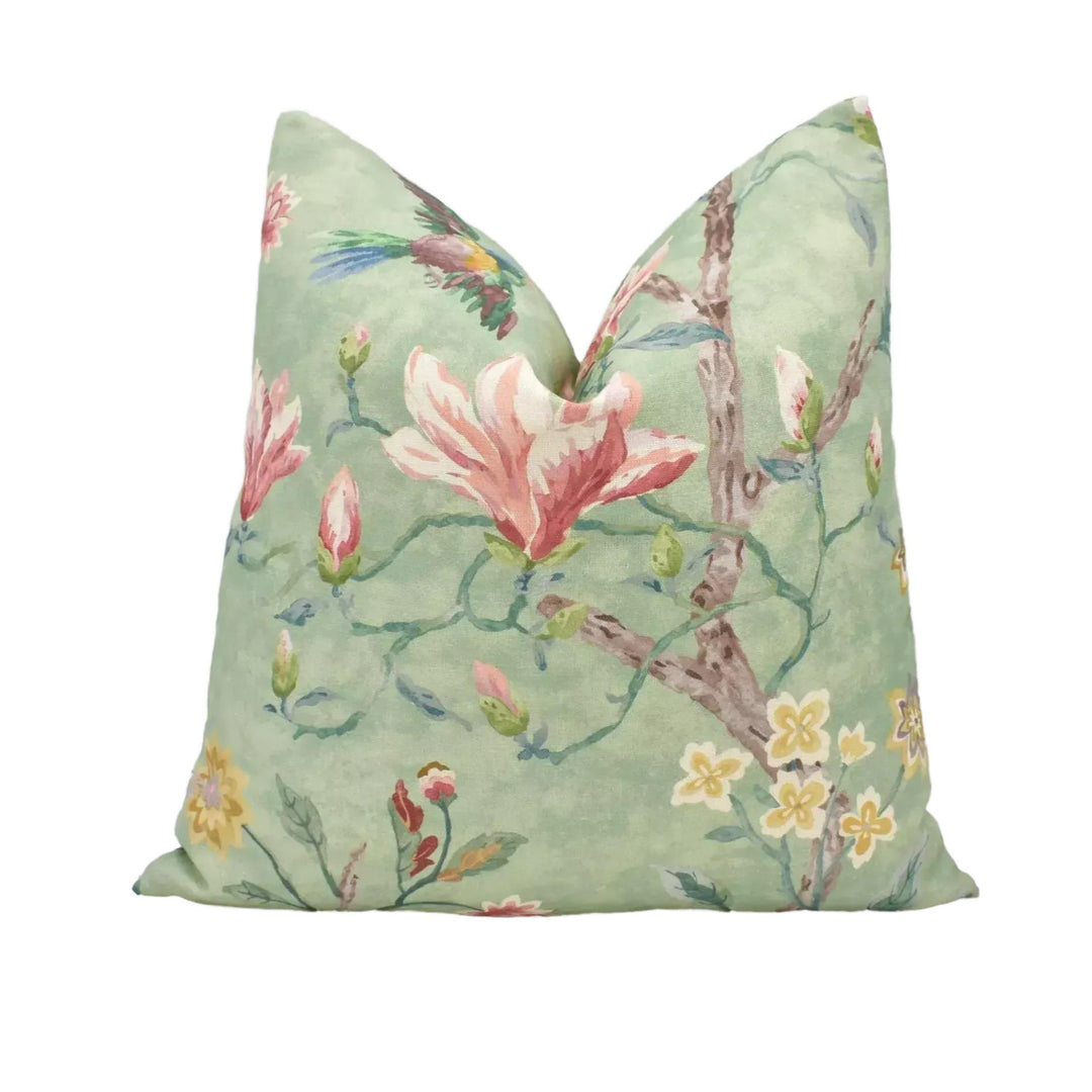 a green pillow with a floral pattern, including pink and yellow flowers, leaves, and a bird.
