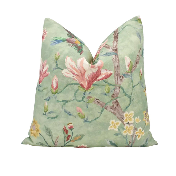 a green pillow with a floral pattern, including pink and yellow flowers, leaves, and a bird.