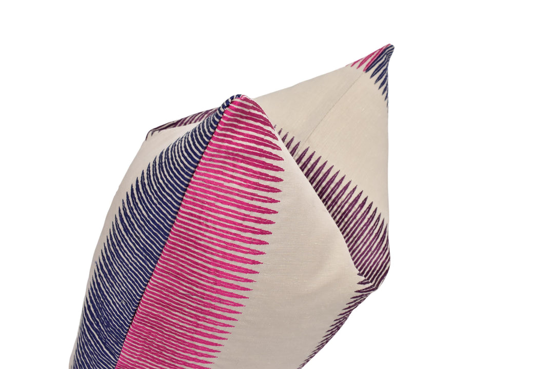 A close-up view of a decorative pillow with a striped pattern in shades of pink and blue.