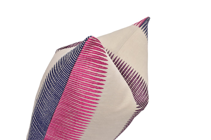 A close-up view of a decorative pillow with a striped pattern in shades of pink and blue.