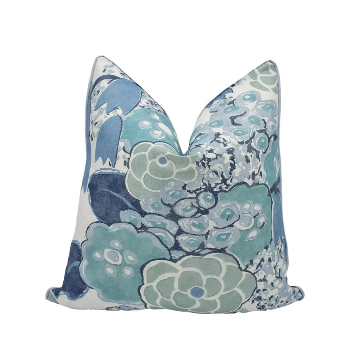 a decorative pillow with a floral pattern in shades of blue and white.