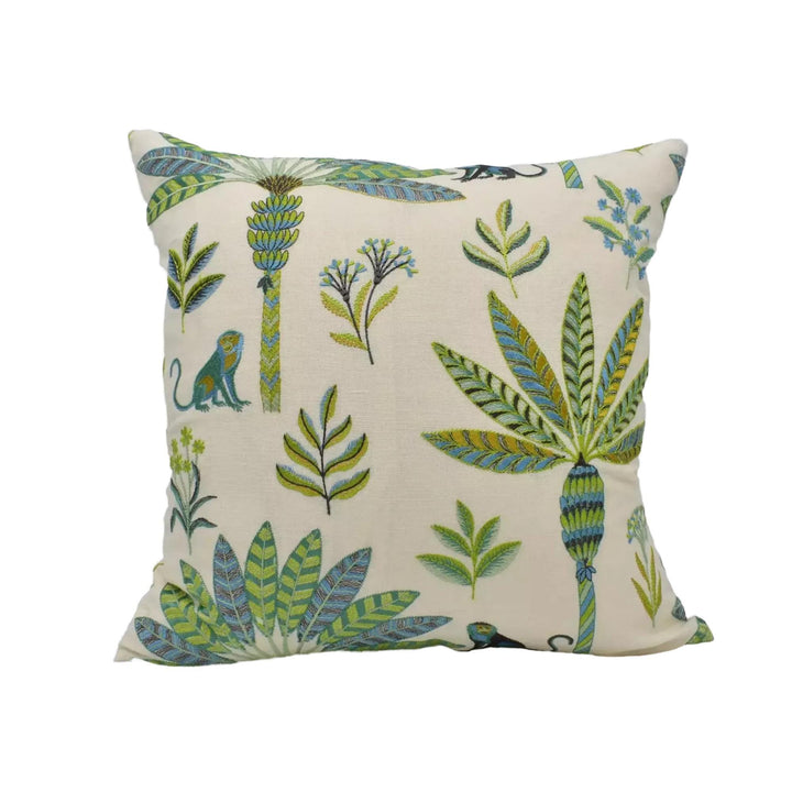 A square throw pillow with a tropical theme, featuring various plants, leaves, and animals in shades of green and blue.