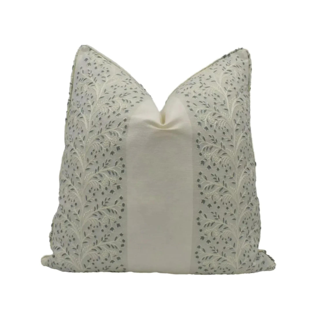 A decorative pillow with a floral pattern in shades of gray and white.