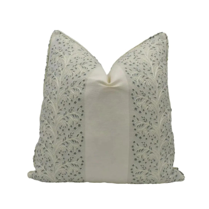 A decorative pillow with a floral pattern in shades of gray and white.