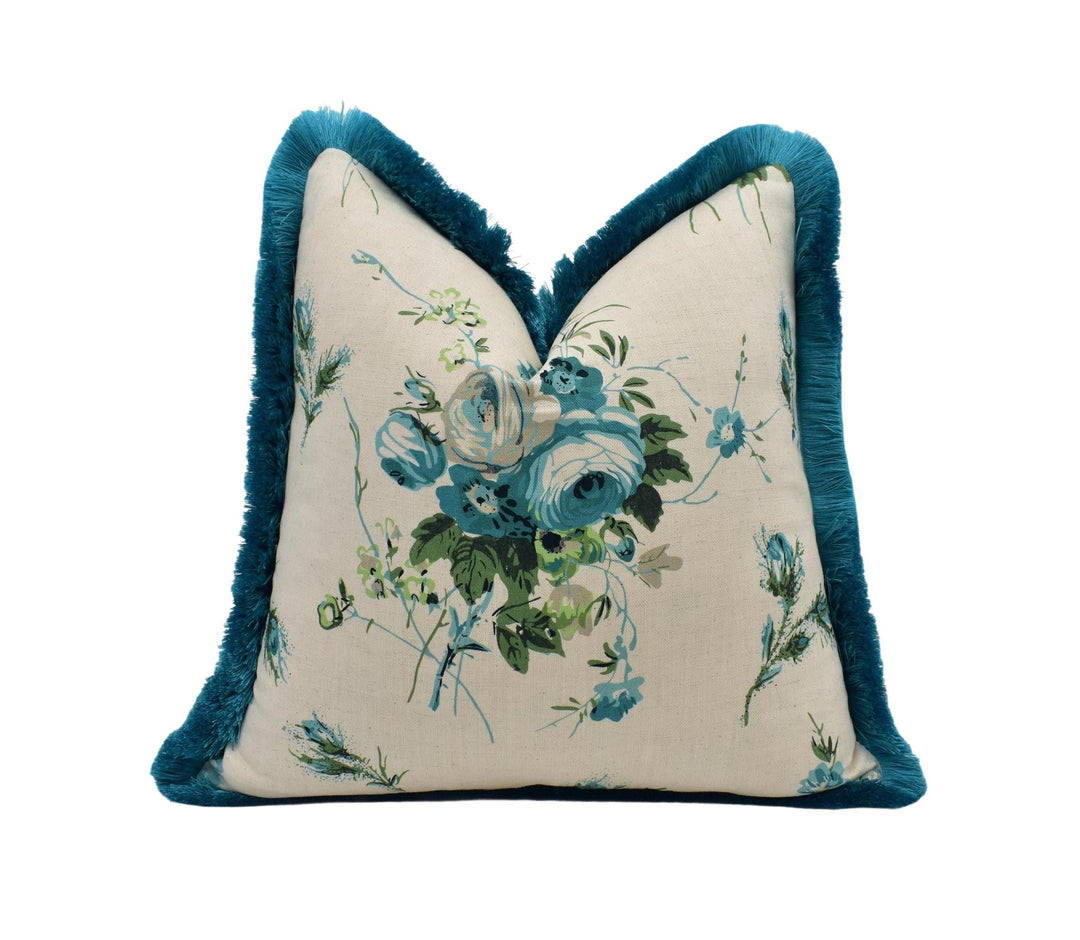 A decorative throw pillow with a floral print and a blue fringe trim.