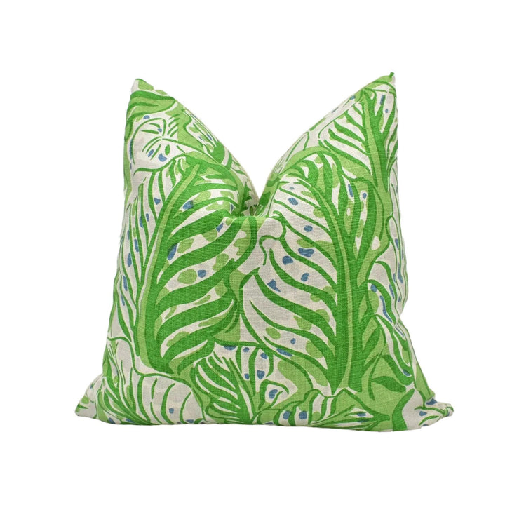 A green and white throw pillow with a leafy, tropical pattern.
