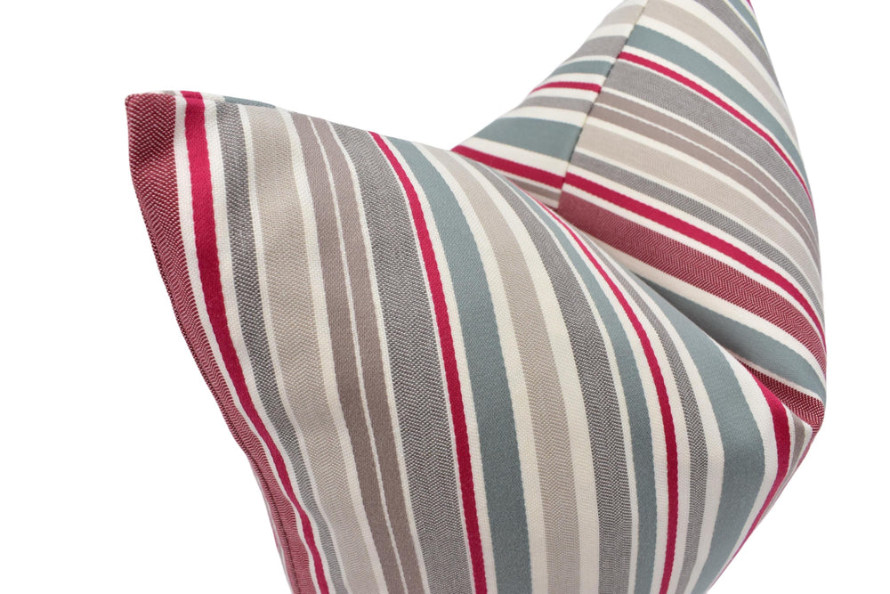 A close-up view of a decorative pillow with a striped pattern in shades of gray, red, and white.