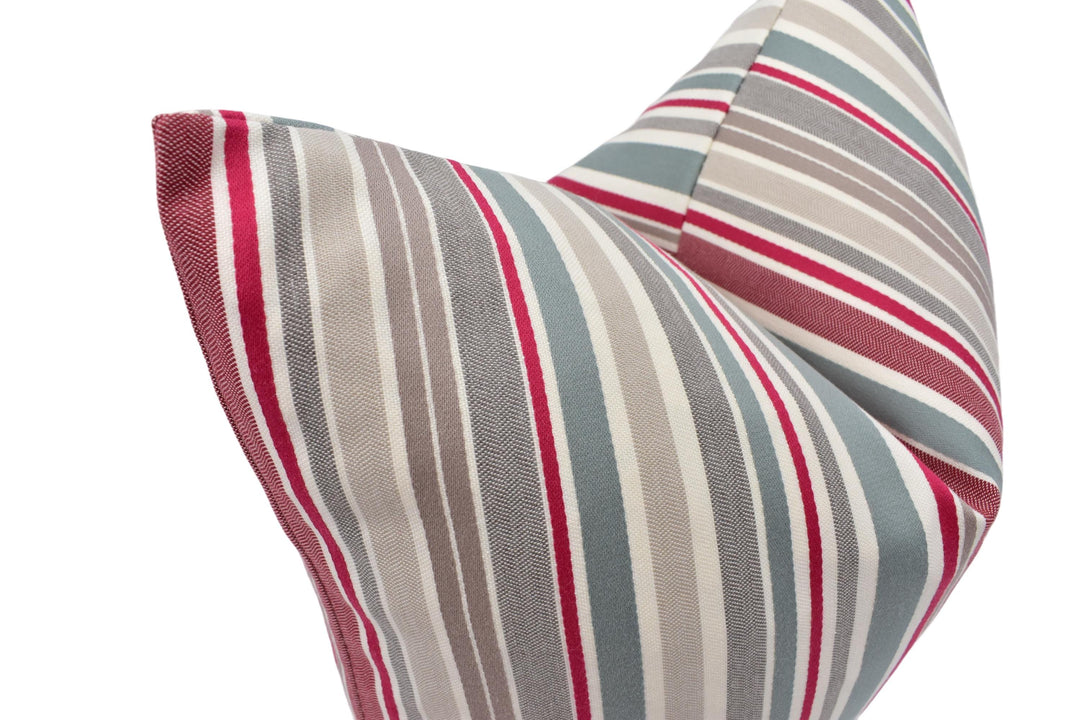 A close-up view of a decorative pillow with a striped pattern in shades of gray, red, and white.
