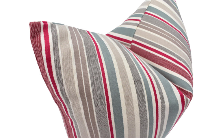 A close-up view of a decorative pillow with a striped pattern in shades of gray, red, and white.