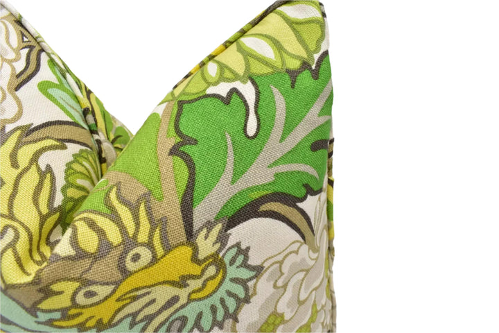 a close-up view of a vibrant, colorful fabric with a floral pattern. The fabric appears to be a pillow or cushion, with a mix of green, yellow, and brown colors. The pattern is intricate and detailed, with various shapes and textures that create a visually appealing design.