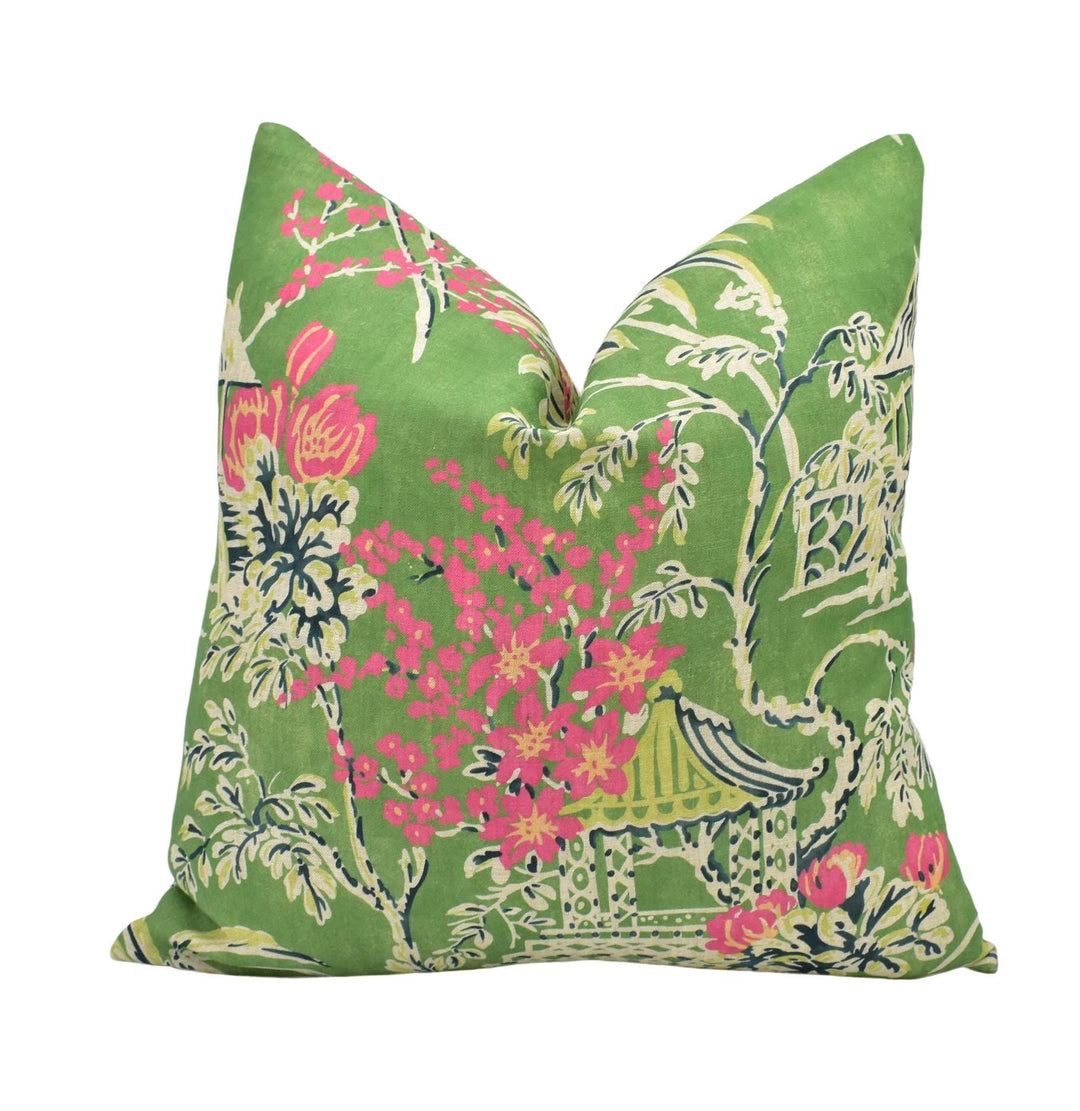 A green throw pillow with a floral pattern in shades of pink and green.