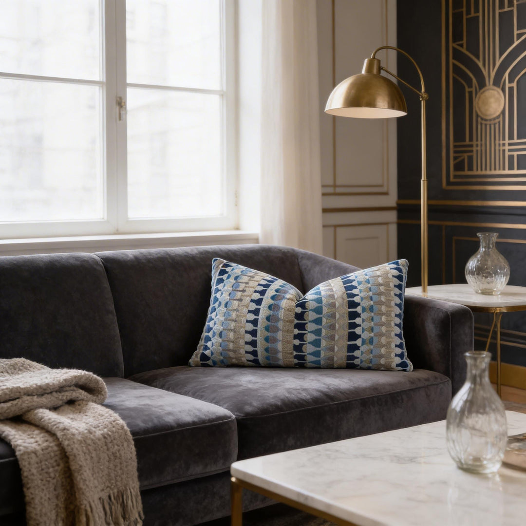 a cozy living room with a plush gray sofa adorned with a patterned throw pillow, a floor lamp, and a glass vase on a side table.