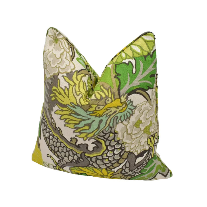 A decorative pillow with a vibrant dragon design in shades of green, yellow, and white.