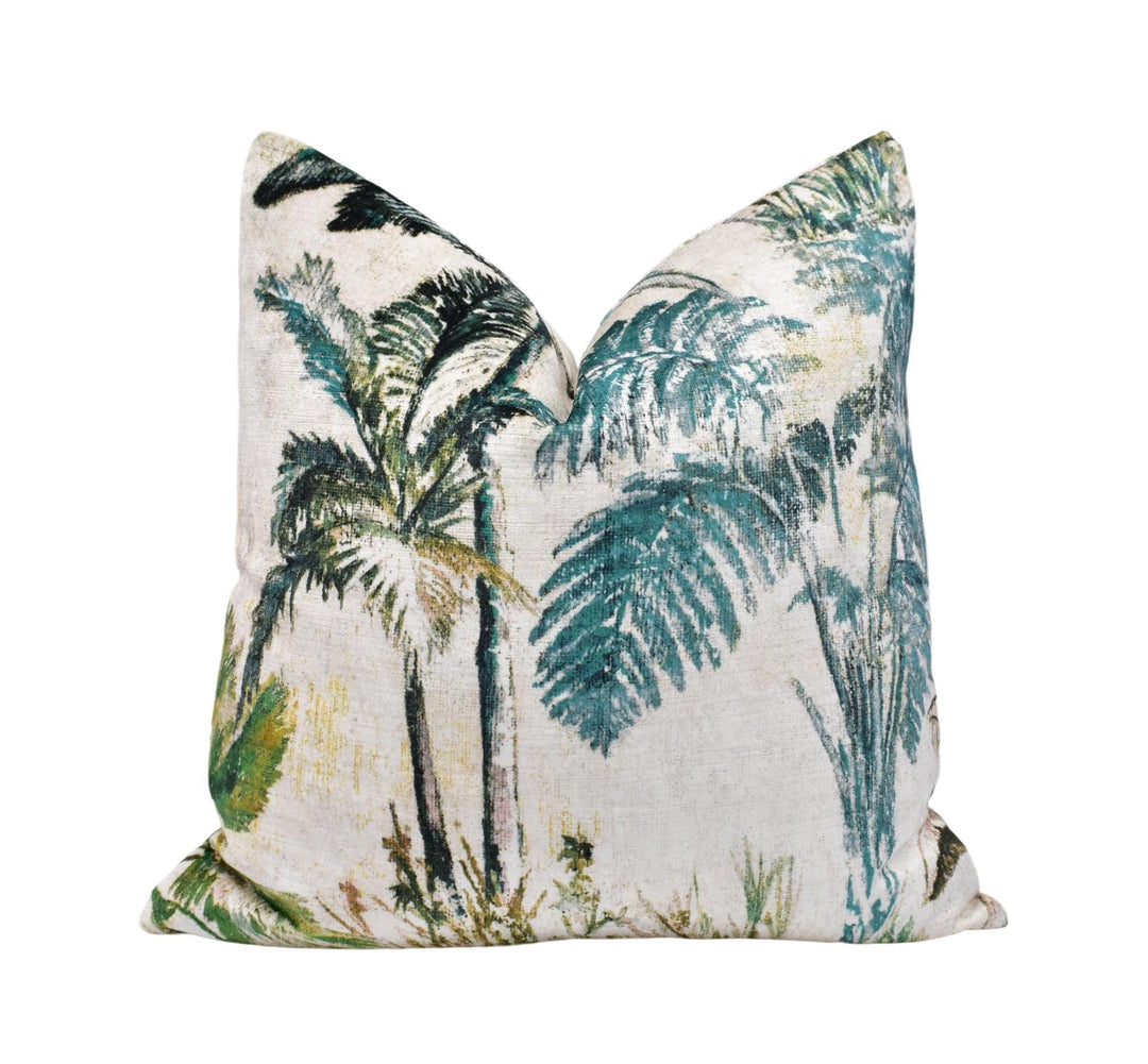 a decorative pillow with a tropical print design, including palm trees and other lush foliage in shades of green and blue.