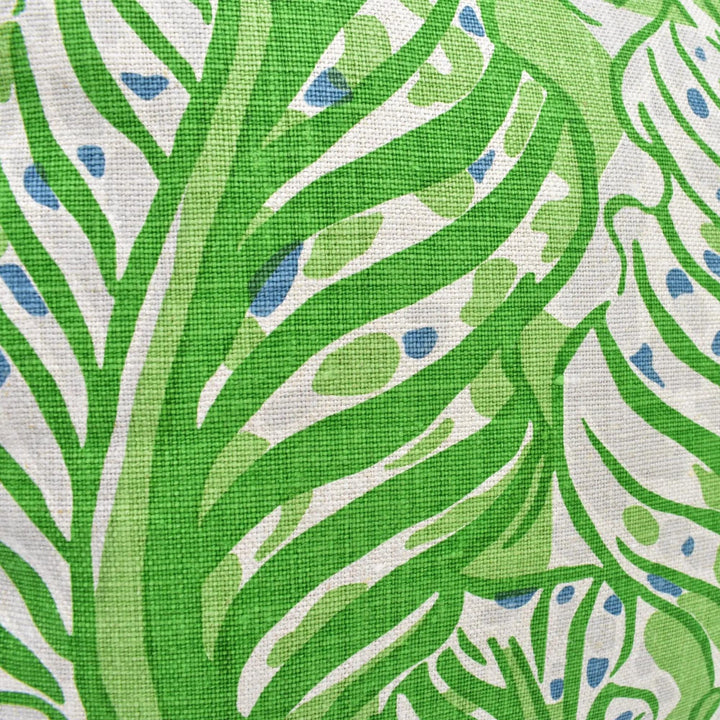 a close-up view of a fabric with a green and white leaf pattern. The fabric appears to be a type of textile, possibly a piece of clothing or a textile product. The leaf pattern is the main focus of the image, with the fabric&
