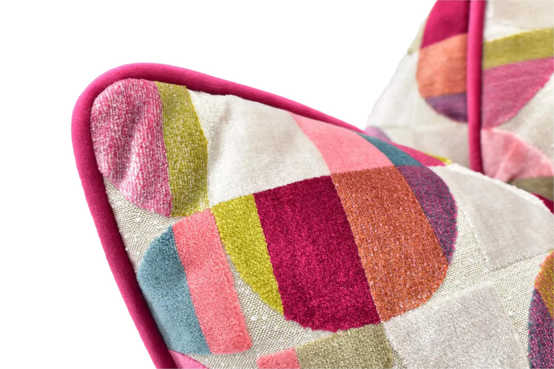 A close-up view of a colorful, patterned pillow with a pink border.