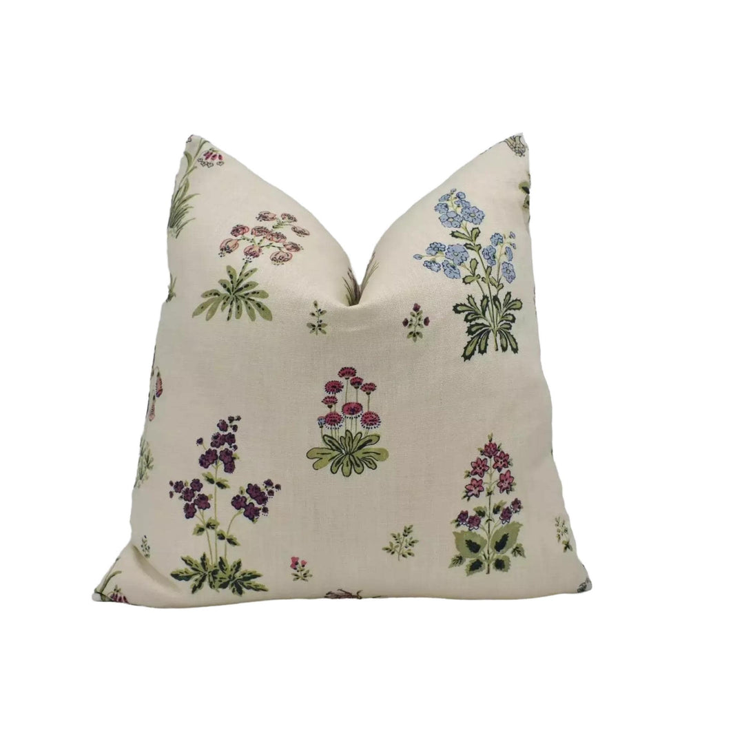A beige pillow with a floral print design featuring various types of flowers and plants.