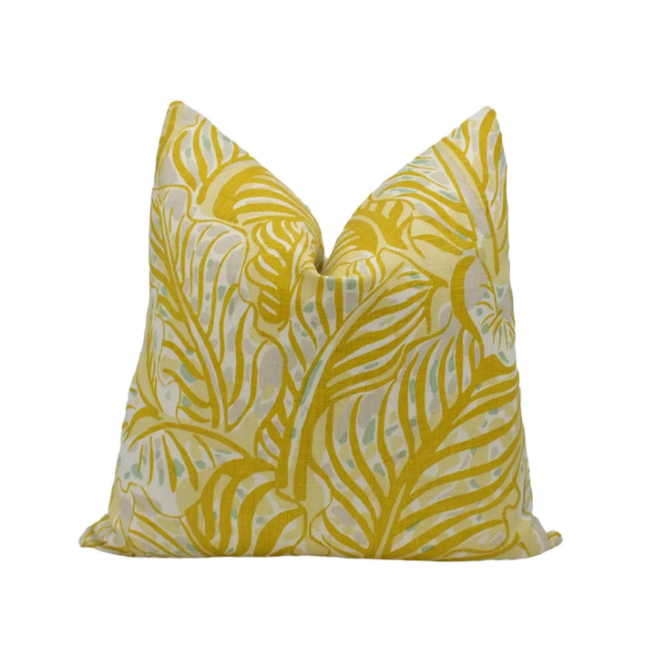 A yellow and white patterned pillow with a tropical leaf design.