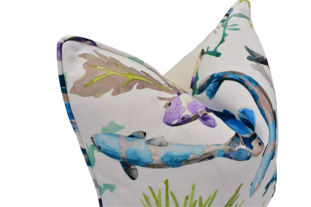 a close-up view of a decorative pillow with a vibrant, colorful print of fish and aquatic plants.