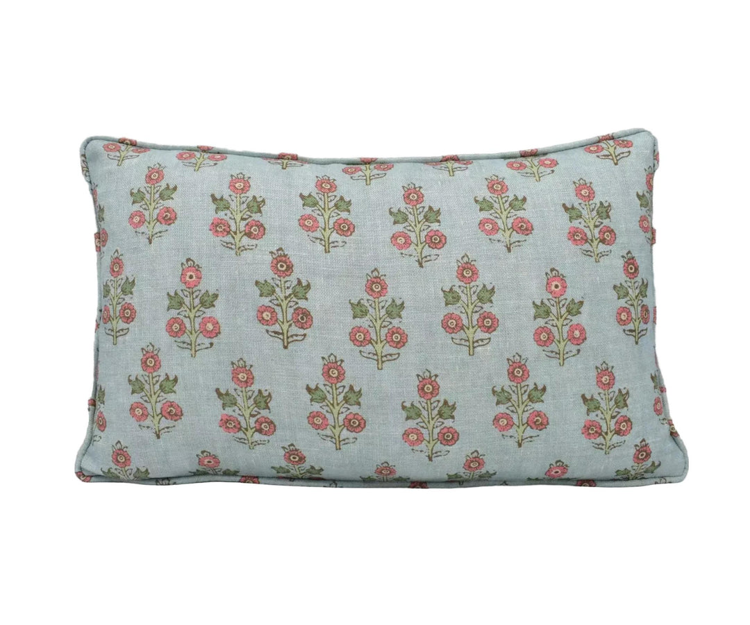 A light blue pillow with a repeating floral pattern of red and green flowers on a white background.
