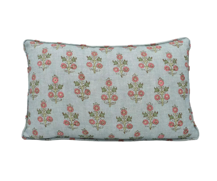 A light blue pillow with a repeating floral pattern of red and green flowers on a white background.